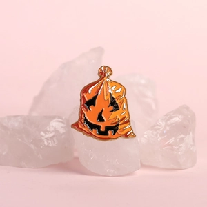 Funny Halloween orange pumpkin evil face enamel pin badge on white crystal stone display