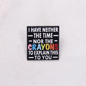 Square black enamel pin featuring rainbow colored crayons and humorous quote on fabric