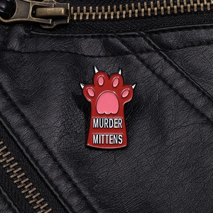 Detail of Murder Mittens cat paw enamel pin on black leather background