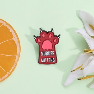 Red cat paw enamel pin with Murder Mittens text on a decorative green background