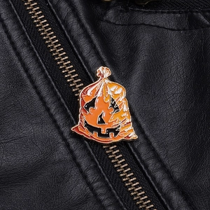 Dettaglio di una spilla smaltata a zucca di Halloween su una giacca di pelle nera