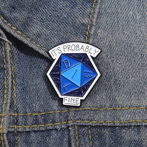 Detail of D20 dice enamel pin with 'IT'S PROBABLY FINE' text on denim jacket