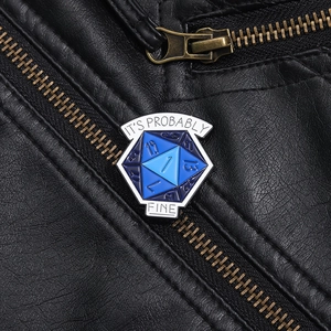 Detail of blue D20 dice enamel pin with It's Probably Fine text on a leather jacket