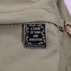 Märchenbuch-Emaille-Pin mit Blumen und Text auf grünem Canvas-Rucksack