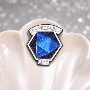 Deep blue D20 dice enamel pin with 'IT'S PROBABLY FINE' text in a decorative shell tray