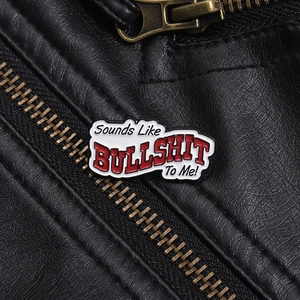 Close-up of BULLSHIT enamel lapel pin on black leather jacket with metal zipper detail