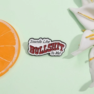 Funny enamel brooch with 'Sounds Like BULLSHIT To Me' text on white background