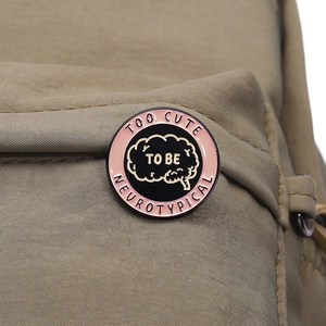 Macro shot of a pink and black enamel pin with brain design on a canvas bag strap