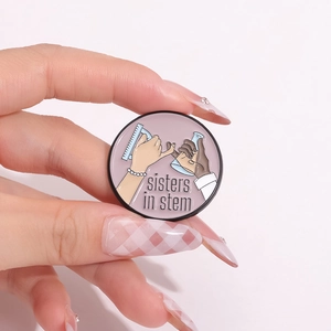Broche en émail avec texte Sisters in STEM et bécher de labo sur fond rose doux