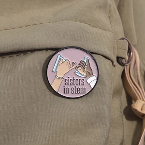 Detail of Sisters in STEM enamel pin with flask and ruler on khaki canvas bag