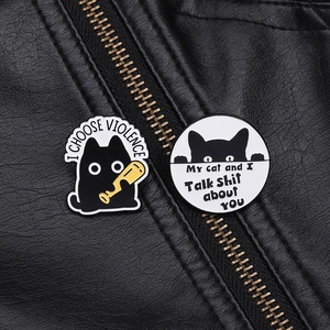Detail of funny black cat enamel pins with humorous text on a black leather jacket
