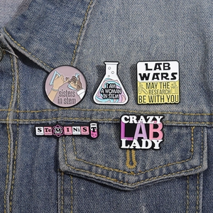 Détail de cinq pin's émaillés STEM fixés sur la poche d'une veste en jean bleue