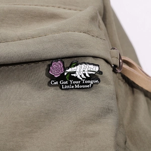 Detail of gothic skeletal hand holding a purple rose enamel pin on a khaki canvas bag
