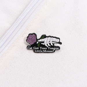 Macro detail of punk skeleton hand holding a purple rose enamel pin on white canvas