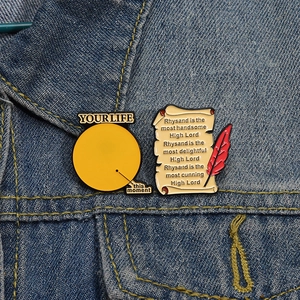 Détail de pin's en émail avec citations et stylo plume sur fond en jean bleu