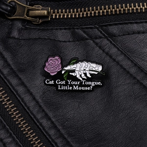 Close-up of skeleton hand holding a purple rose enamel pin on a black leather jacket