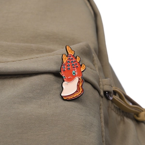 Vue détaillée d'un pin's émaillé poisson sandwich fixé sur un sac à dos en toile kaki