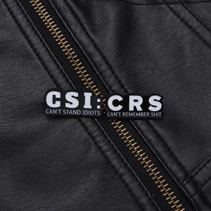 Macro shot of CRS and CSI enamel pins with funny slogans on a black leather jacket