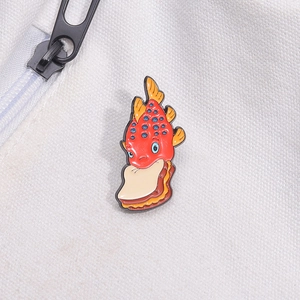 Close-up of a cute red fish enamel pin with a sandwich on a white canvas bag
