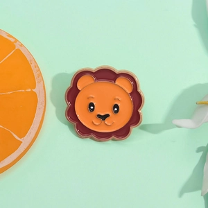 Cute cartoon lion enamel brooch with orange face and red mane on mint green background