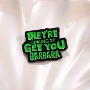 Enamel pin with green lettering on black background featuring a movie quote design