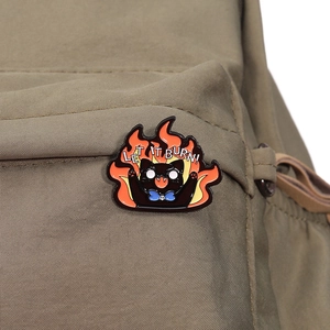 Detailed enamel pin of a screaming black cat in flames with 'LET IT BURN!' on canvas bag