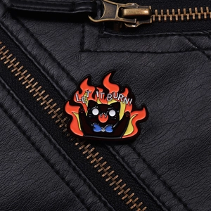 Detail of Let It Burn cartoon black cat enamel pin on a black leather jacket texture