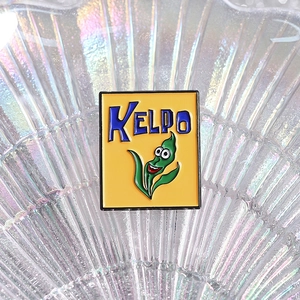 Cartoon Kelpo cereal enamel pin with green kelp character on bright yellow background