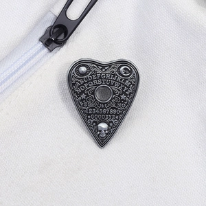 Detailed shot of Gothic Ouija planchette metal badge pinned on white canvas material