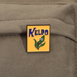 Detail of a square enamel Kelpo kelp pin badge on khaki canvas texture fabric
