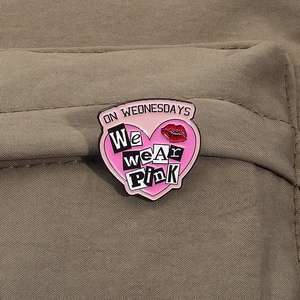 Vue macro d'un pin's coeur rose émaillé avec texte On Wednesdays We Wear Pink sur toile brune