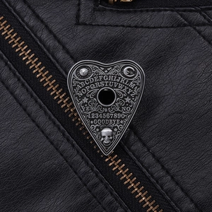 Macro detail of gothic heart ouija board pin with skull relief on black leather jacket