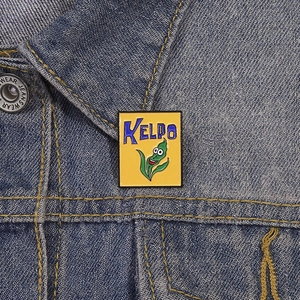 Detailed macro view of yellow Kelpo enamel pin on blue denim fabric background