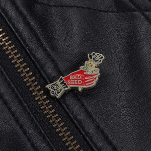 Detail van een emaille speld met hand en witte roos op een zwart leren jack textuur