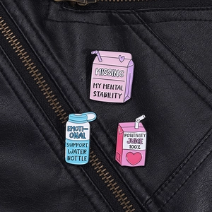 Three creative enamel pins with funny slogans on a black leather jacket background