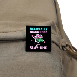 Badge en émail grenouille avec chapeau de cow-boy rose sur un sac à dos en toile kaki