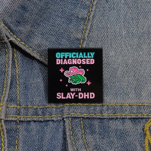 Épinglette grenouille avec chapeau de cowboy rose et texte SLAY-DHD sur jean