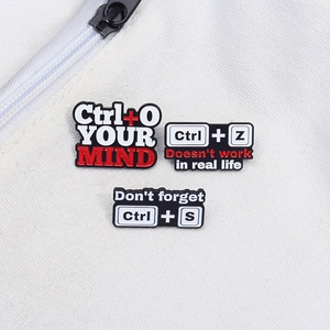 Detail of keyboard shortcut enamel pins showing Ctrl+O, Z, S on canvas background