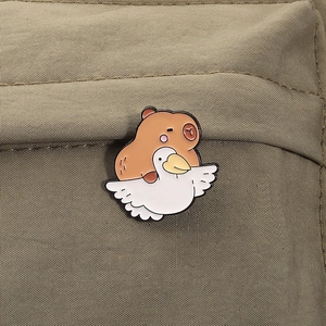 Gros plan d'un pin's émaillé capybara mignon sur un fond en tissu vert aux couleurs vives