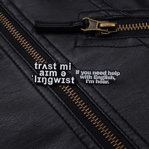 Close-up of minimalist black enamel linguist pins on a textured leather jacket