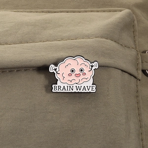 Close-up of pink enamel brain wave brooch pinned on khaki canvas fabric background