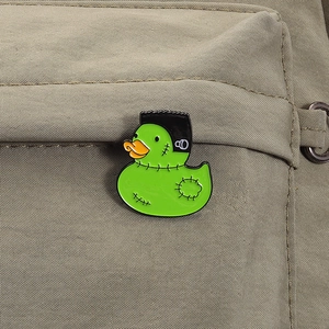 Macro detail of Frankenstein duck enamel pin on a khaki canvas backpack background