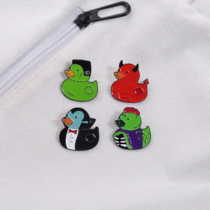 Detailed view of four colorful Halloween duck enamel pins on white canvas fabric