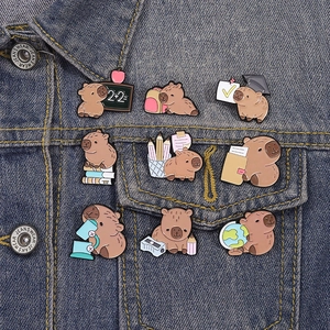 Cute Capybara school themed enamel pins set on denim jacket with educational motifs