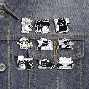 Close-up of 9 cartoon black and white cat enamel pins pinned on a blue denim jacket