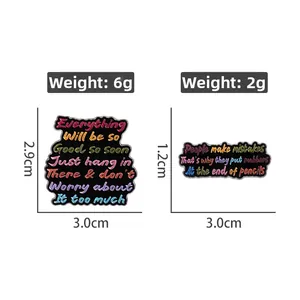 Detail of black enamel pins featuring colorful motivational quotes and metal borders