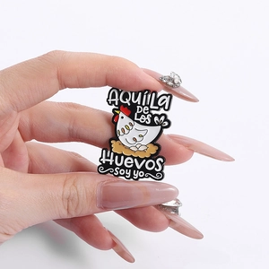 Funny cartoon hen enamel pin badge with Spanish text held in hand against white background