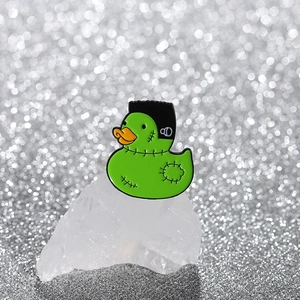 Épingle en émail de canard vert style Frankenstein sur un fond de cristal blanc