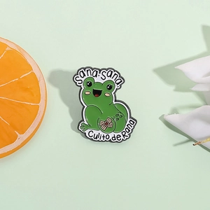 Cute green frog enamel pin featuring Sana Sana Culito de Rana text on mint background