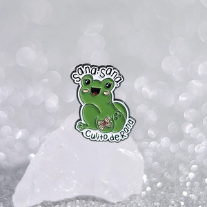 Cute green cartoon frog enamel pin with Sana sana Culito de Rana text on white crystal